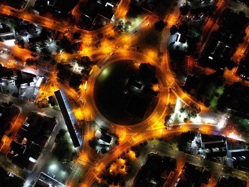 A stunning aerial view of a city roundabout lit up at night with vibrant streetlights and