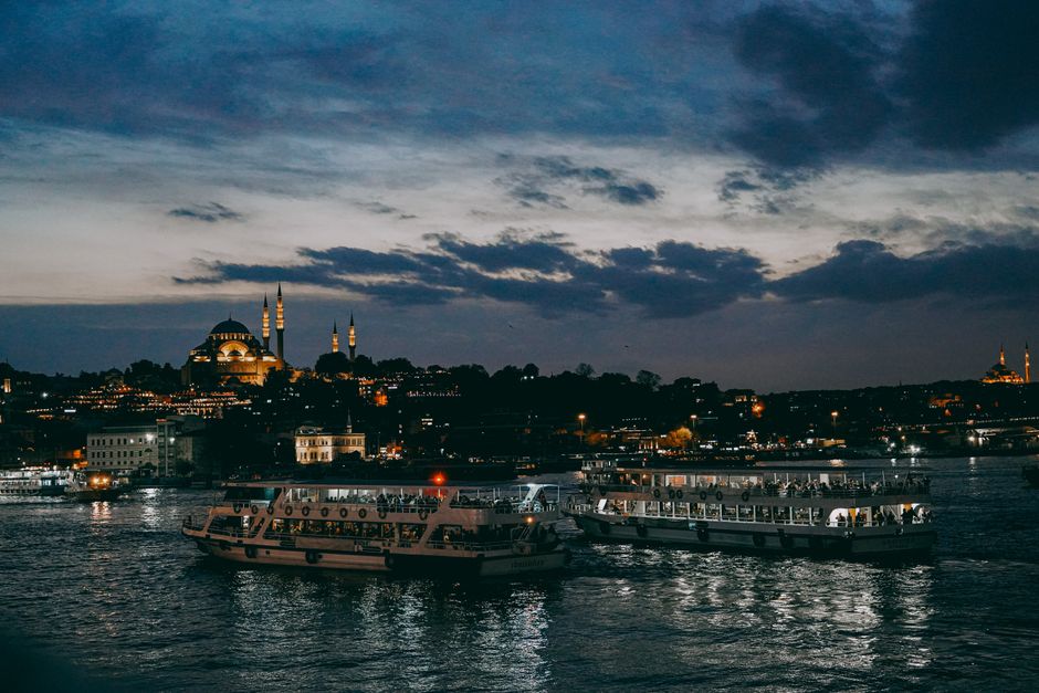 Boats sailing on Bosphorus with Istanbul's iconic skyline at twilight.