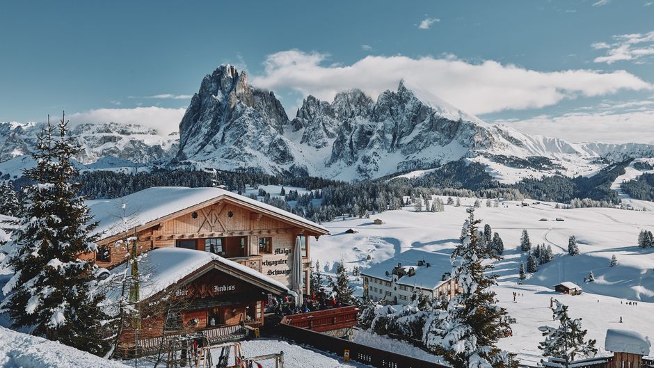 Breathtaking winter view of snow-covered Dolomites in Italy with a charming wooden chalet.