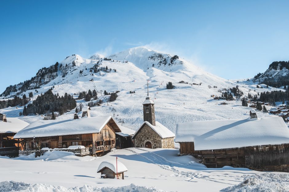 Charming village nestled in snowy mountains under a clear blue sky. Perfect winter scene.