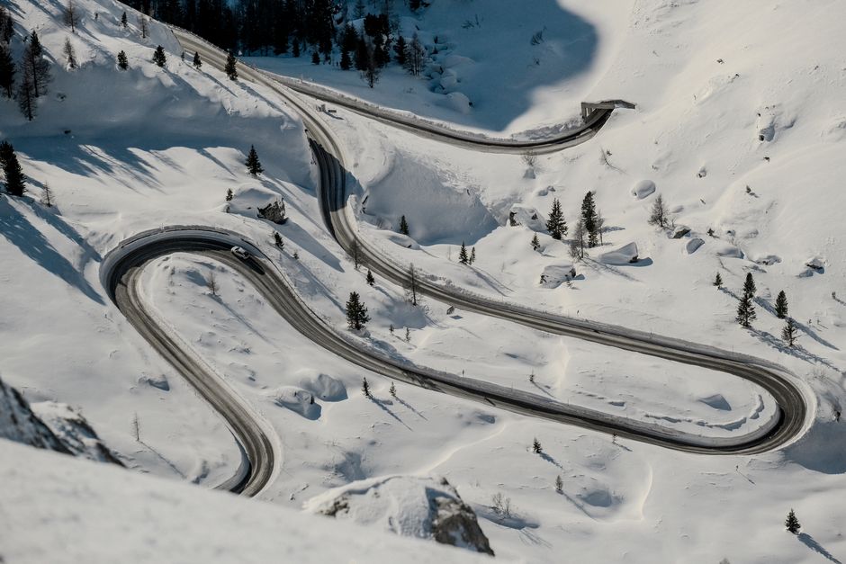 A scenic aerial view of a winding road through snow-covered mountains, ideal for winter travel themes.