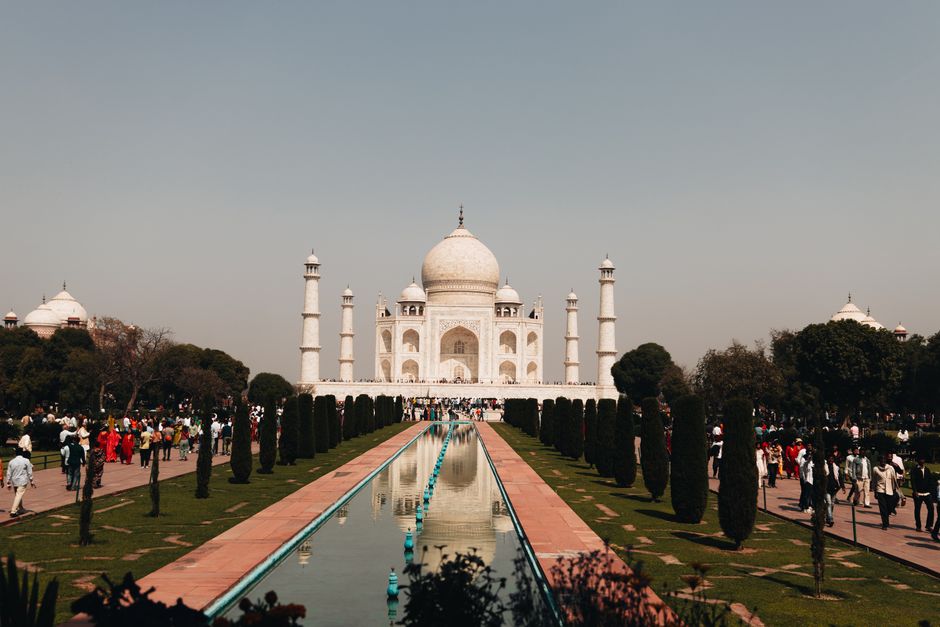 A beautiful view of the Taj Mahal with tourists and reflection in Agra, India.