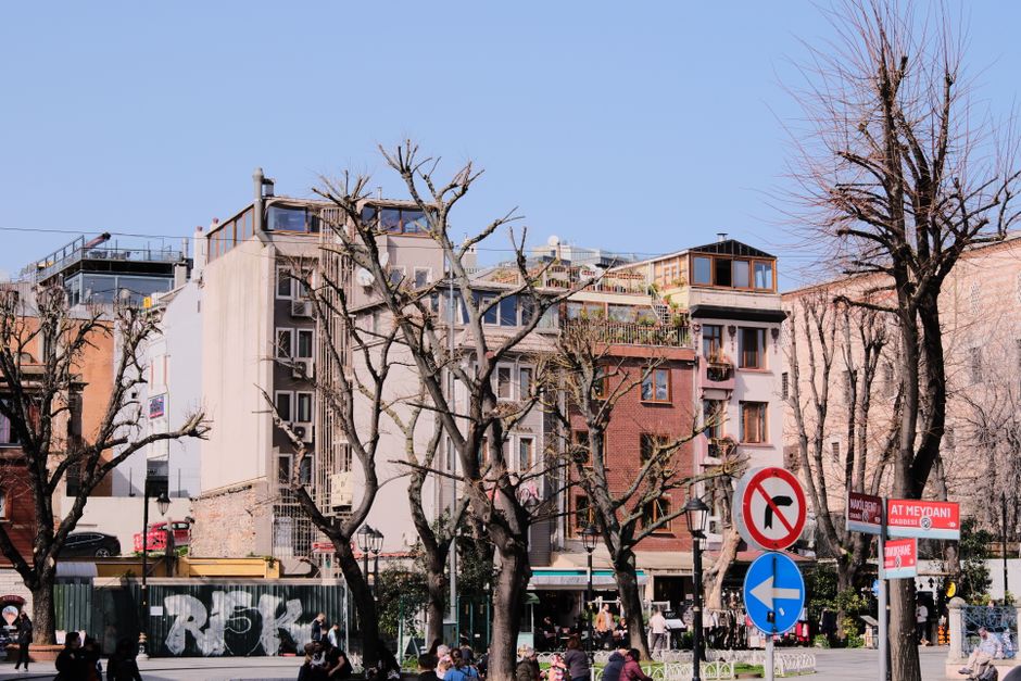 Lively city street with bare winter trees and colorful buildings.