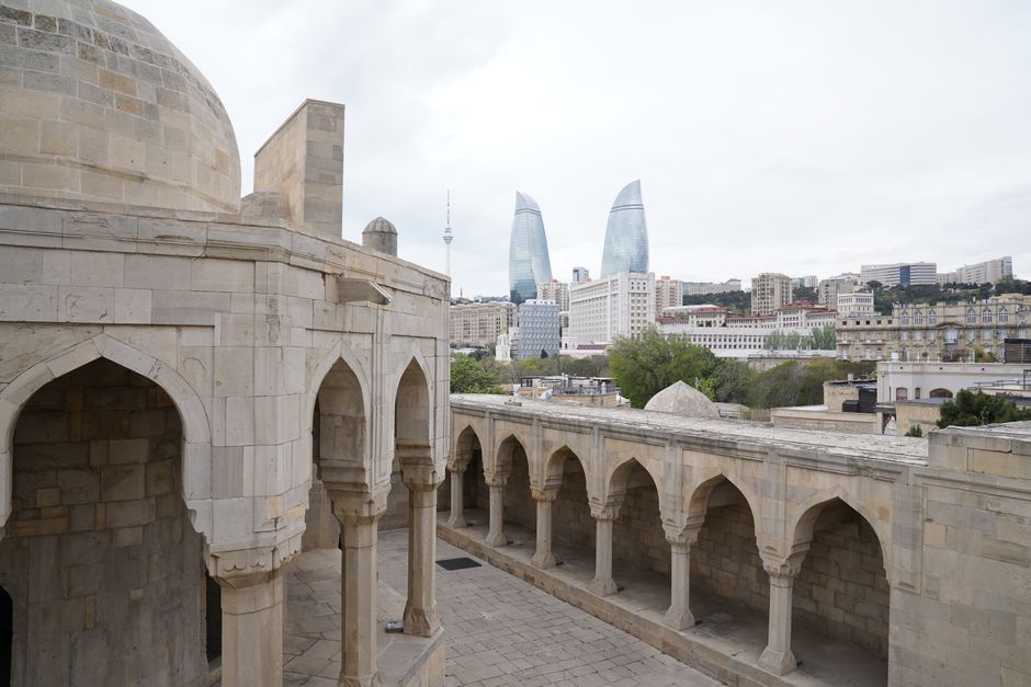 Ancient architecture meets modern skyline in Baku with Flame Towers in the background.