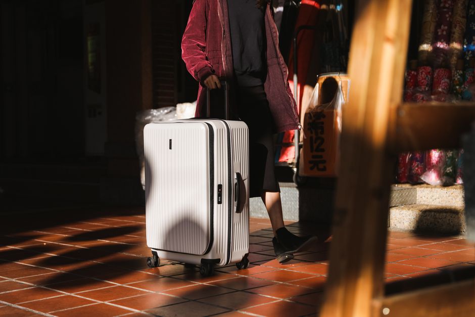 Woman walking with suitcase in city, showcasing travel and urban exploration.