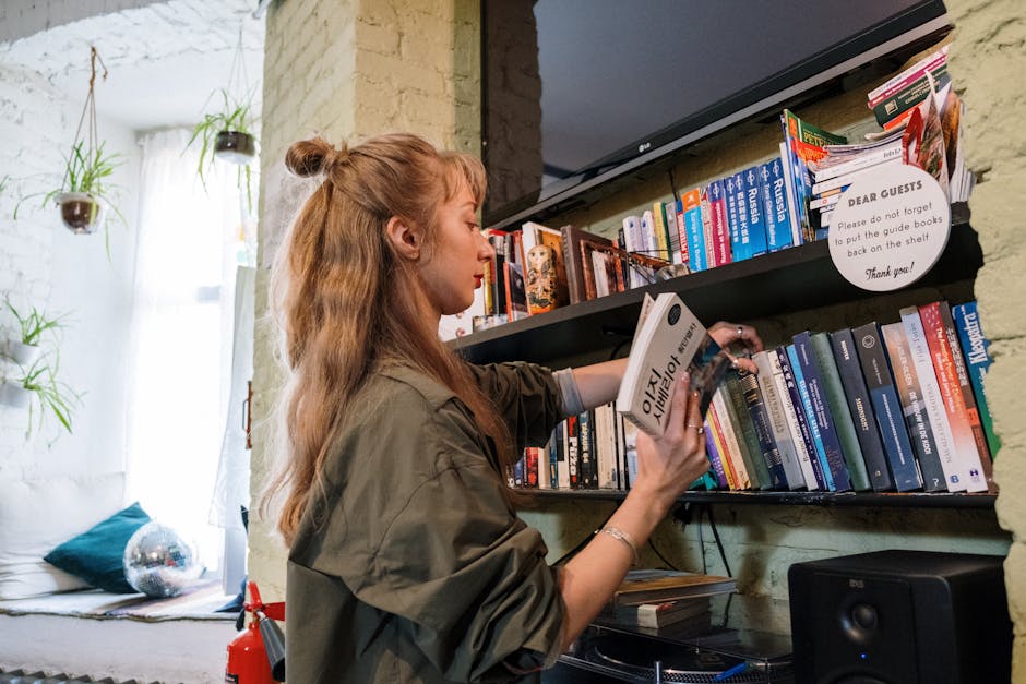 A woman browsing books on a shelf in a cozy indoor setting, capturing a love for literature and education.